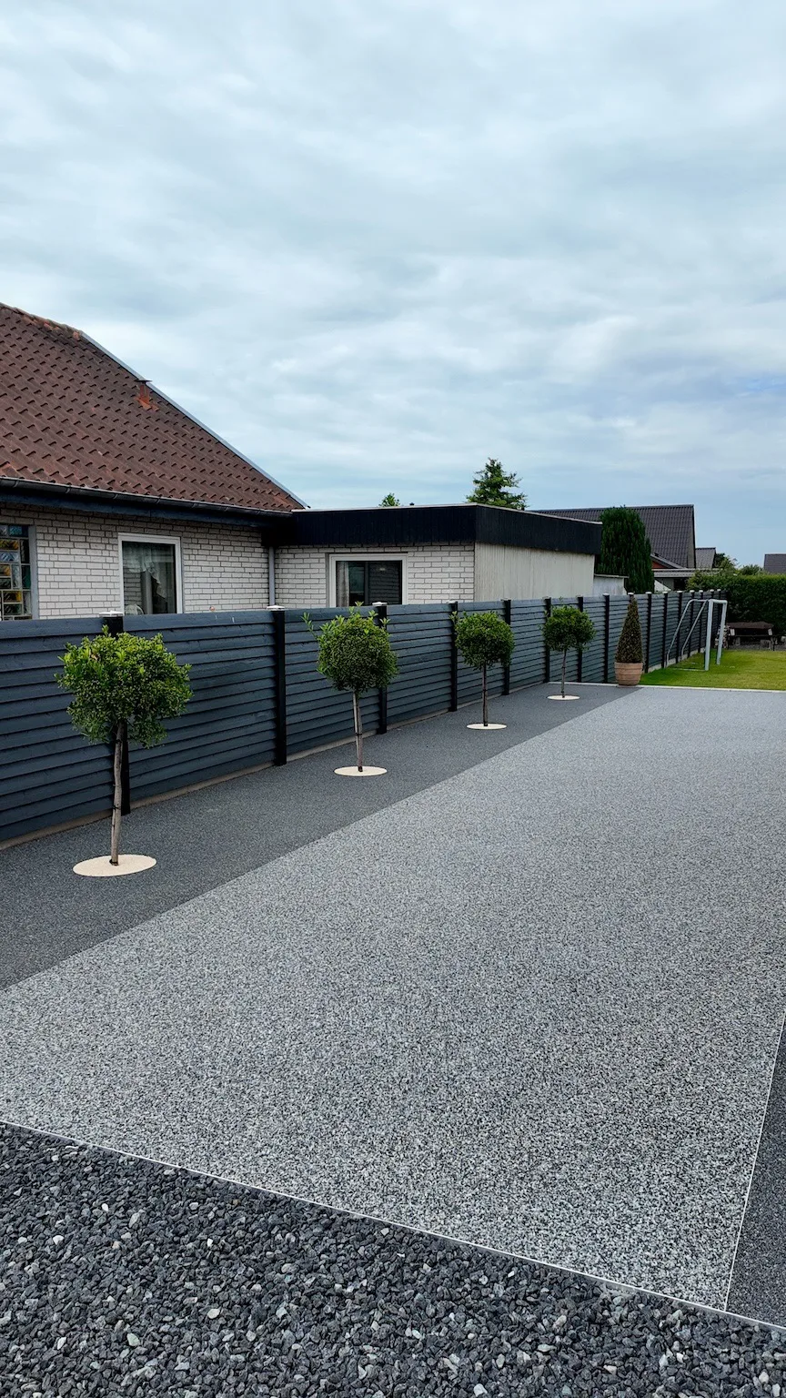 Helstøbt stenbelægning på gangsti til baghaven langs bøgetræer i espalier og mørkt hegn