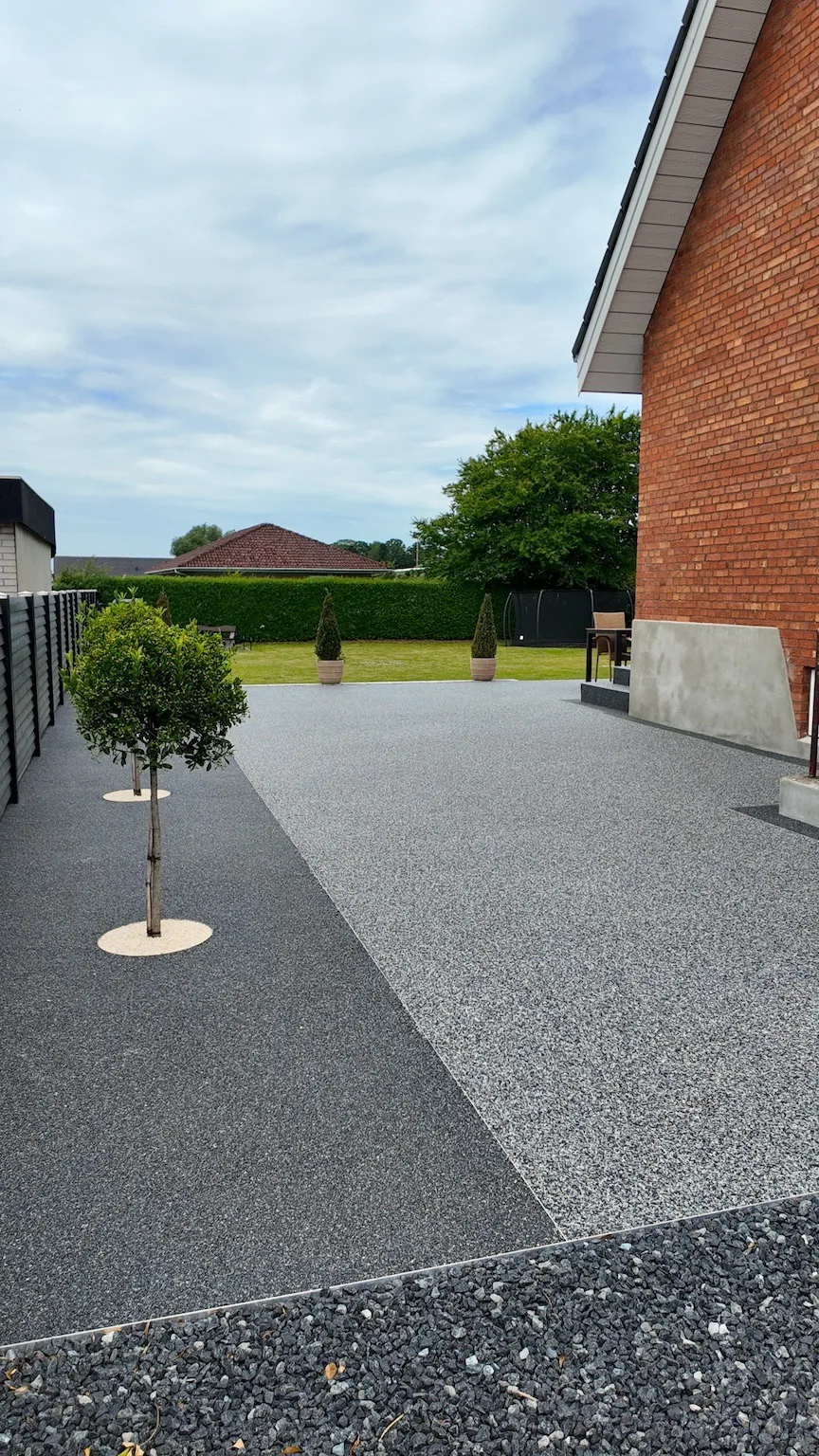 Resin stenbelægning terrasse ved gavlen med grå og sort granitkant